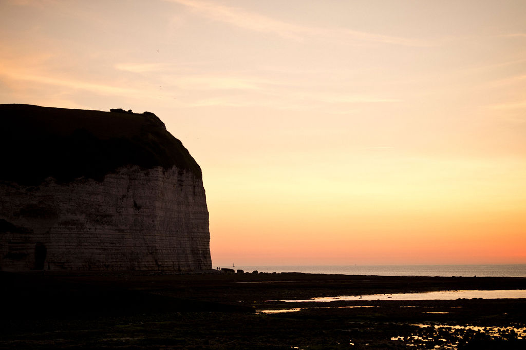 Falaise avec le couché de soleil qui tombe sur la mer