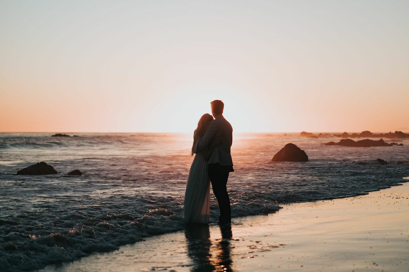 Lune de miel : Comment bien préparer son voyage de noces ? - Couple qui regarde le coucher de soleil sur la mer en vacances